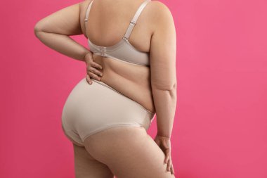Pembe arka planda bej iç çamaşırlı şişman kadın, yakın plan. Büyük boy model