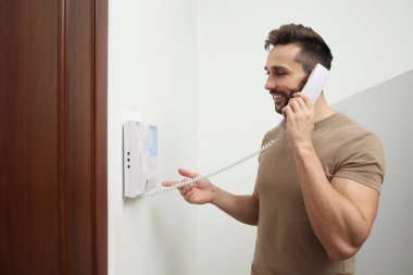 Cep telefonu olan bir adam dahili telefona cevap veriyor.