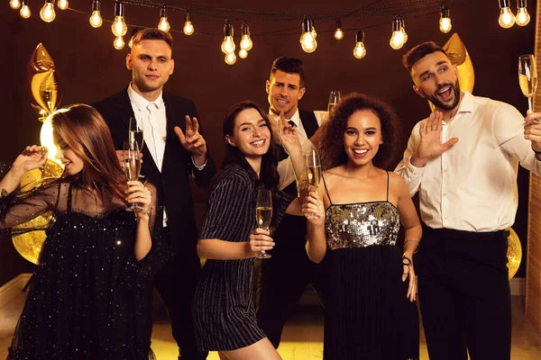 Mutlu arkadaşlar ve köpüklü şarap kadehleri içeride yeni yılı kutluyor.