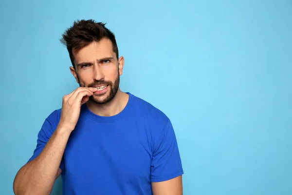 Man Biting His Nails Light Blue Background Space Text — 图库照片