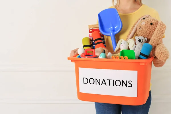 Woman Holding Donation Box Child Toys Light Background Closeup Space — Stockfoto