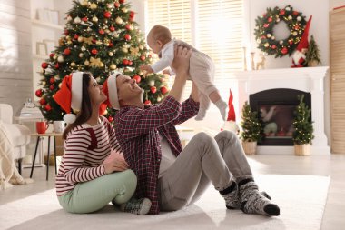 Mutlu bir aile ve yerde şirin bir bebek Noel için dekore edilmiş bir odada