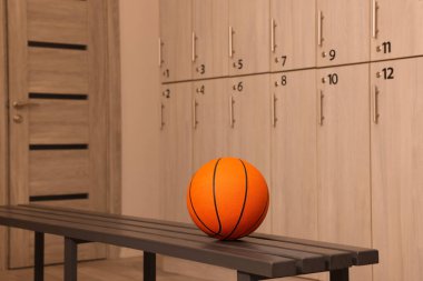 Soyunma odasındaki ahşap bankta turuncu basketbol topu