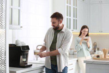 Genç adam mutfakta modern kahve makinesi kullanıyor.