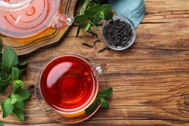 Bir fincan taze nane ve kuru yapraklı aromatik siyah çay, düz bir masa. Metin için boşluk