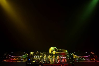 Modern DJ denetleyici ve kulaklıklar siyah arkaplanda ışık demetleri altında