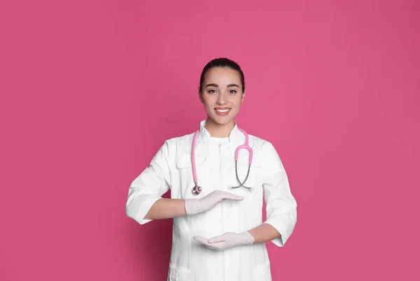 Krásný Mladý Lékař Drží Něco Růžovém Pozadí — Stock fotografie