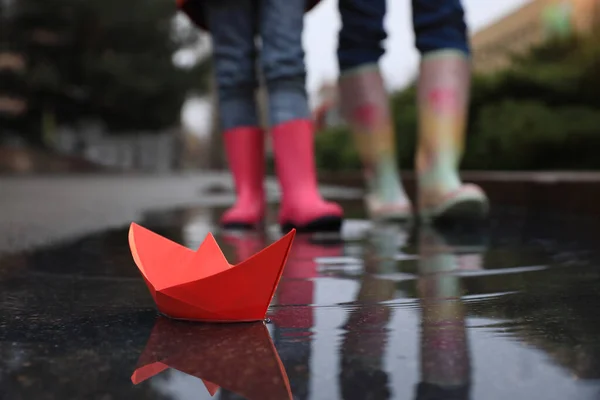 小さな女の子とともに彼女の母歩く屋外で 焦点を当て紙のボートで水たまり — ストック写真