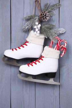 Gri ahşap duvarda Noel süsü asılı bir çift buz pateni.