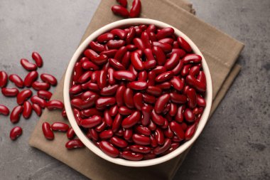 Kase içinde çiğ kırmızı böbrek fasulyesi ve gri masada peçete, düz yatıyordu.