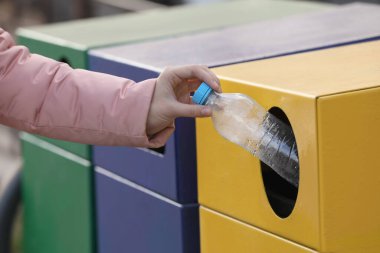 Dışarıdaki çöp kutusuna plastik şişe atan kadın, yakın plan. Atık sıralama