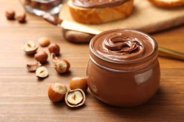 Lezzetli çikolata fındıklı cam kavanoz ve ahşap masada fındık. Metin için boşluk