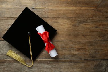 Mezuniyet şapkası ve diploması ahşap masada, düz yatıyordu. Metin için boşluk