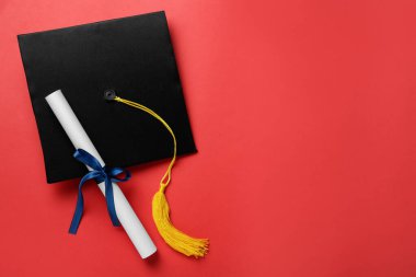Kırmızı arka planda mezuniyet şapkası ve diploması var. Metin için boşluk