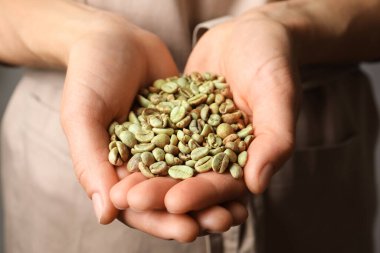 Yeşil kahve çekirdeği yığını tutan kadın, yakın plan.