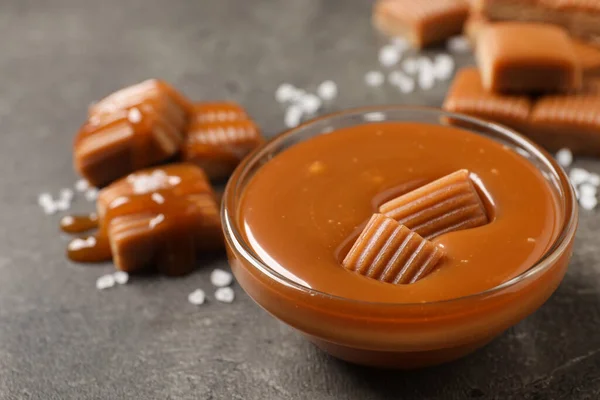 Tasty Salted Caramel Candies Glass Bowl Grey Table Closeup — Stockfoto