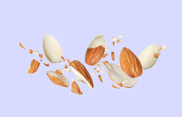 Pieces Tasty Almonds Falling Light Grey Background — Stock Photo, Image