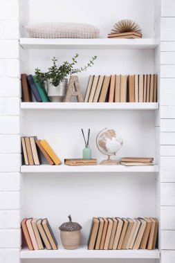 Collection of books and decor elements on shelves indoors clipart