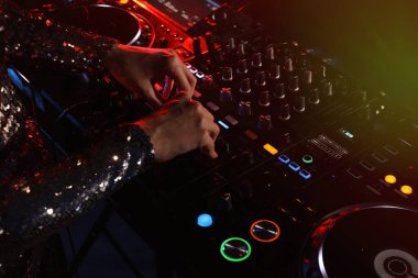 DJ, gece kulübünde modern konsol karıştırıcısında müzik yaratıyor.