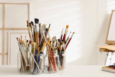 Stüdyoda beyaz masada farklı boya fırçaları, mesaj için yer. Sanatçının işyeri