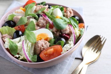 Beyaz ahşap masada servis edilen konserve ton balığı ve sebzeli bir kase lezzetli salata.