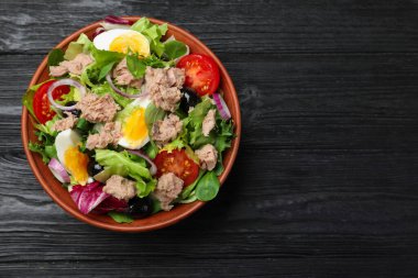 Bir kase lezzetli salata, konserve ton balığı ve siyah ahşap masa üzerinde sebzeler, üst manzara. Metin için boşluk