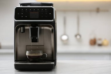 Modern elektrikli espresso makinesi mutfakta beyaz mermer tezgahta kahve yapıyor.