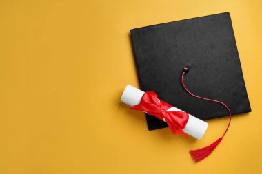 Sarı arka planda mezuniyet şapkası ve diploması var. Metin için boşluk