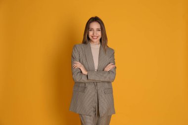 Sarı arka planda şık takım elbiseli güzel bir genç kadının portresi. İş kıyafeti