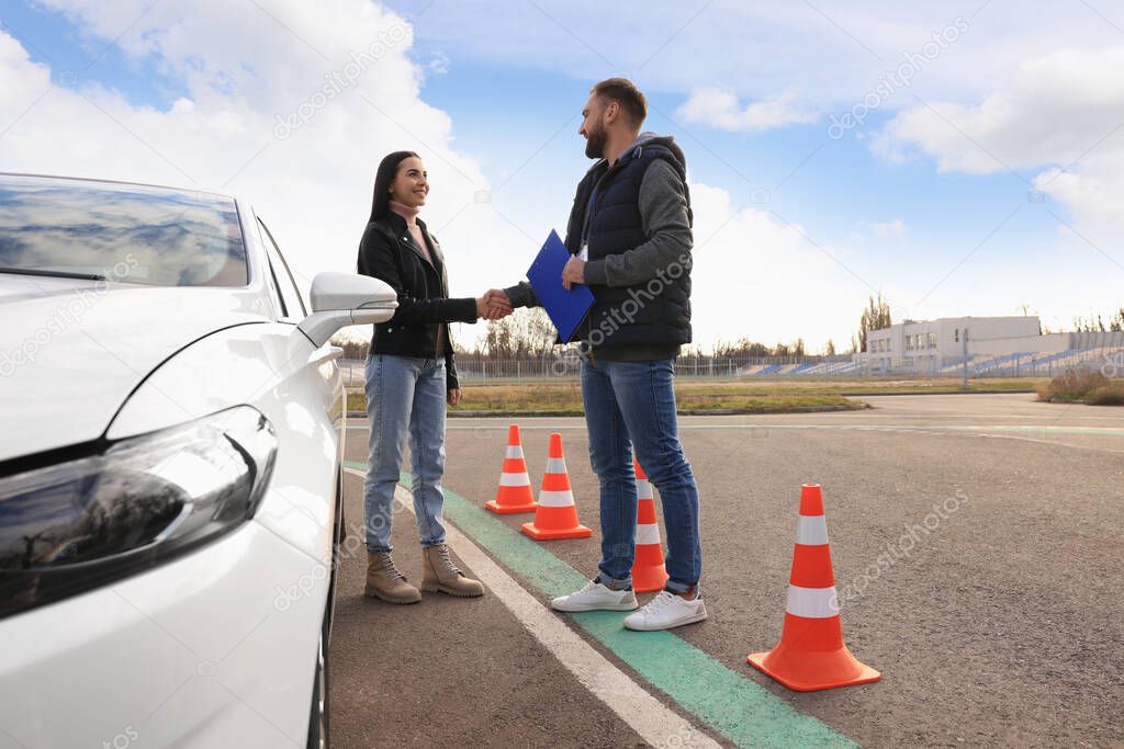 Young woman with instructor near car at driving school test track