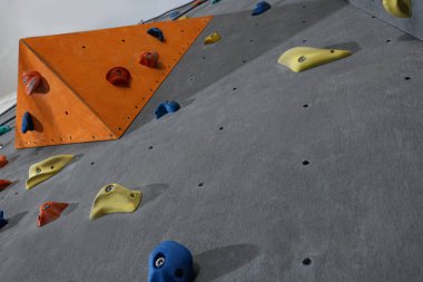 Climbing wall with holds in gym, low angle view. Extreme sport