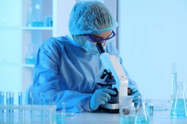 Laboratuvarda mikroskopla çalışan bir bilim adamı. Tıbbi araştırma