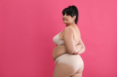 Pembe arka planda bej iç çamaşırlı, kilolu güzel bir kadın. Mesaj için yer var. Büyük boy model