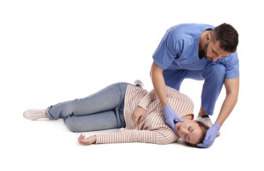 Üniformalı doktor beyaz arka planda baygın bir kadına ilk yardım yapıyor.