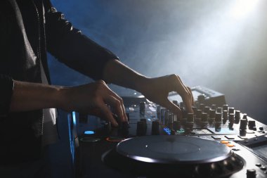DJ, gece kulübünde modern konsol karıştırıcısında müzik yaratıyor.