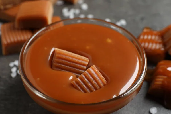 Tasty Salted Caramel Candies Glass Bowl Grey Table Closeup — Stockfoto