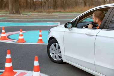 Trafik konisiyle test pistindeki genç adam. Sürücü kursu
