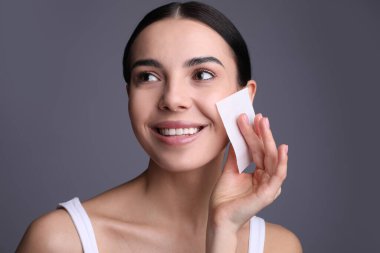 Gri arka planda matlaştırıcı mendil kullanan güzel kadın