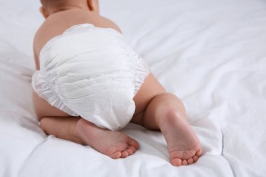 Beyaz yatakta, kuru, yumuşak bezli, şirin bir bebek.