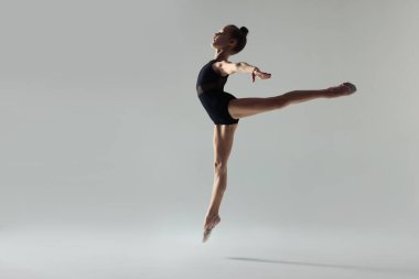 Küçük sevimli jimnastikçi beyaz arka planda tek başına sıçrıyor.