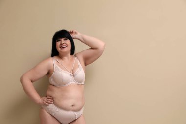 Bej arka planda iç çamaşırlı, kilolu güzel bir kadın, mesaj için yer var. Büyük boy model