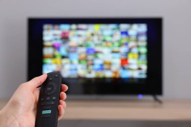 Televizyonda uzaktan kumandayla kanal değiştiren bir kadın. Metin için boşluk