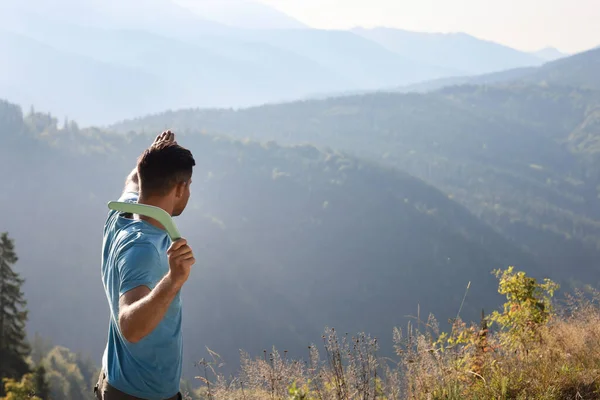 Man throwing boomerang in mountains on sunny day, space for text