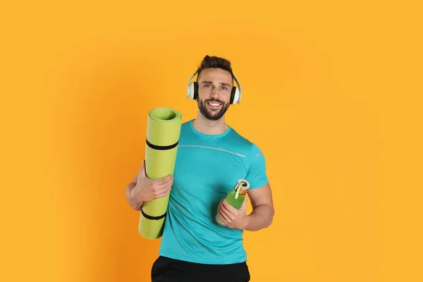 Handsome Man Yoga Mat Headphones Bottle Yellow Background — Zdjęcie stockowe