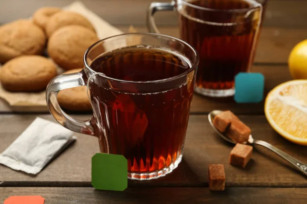 Tea bags in glass cups of hot water and sugar cubes