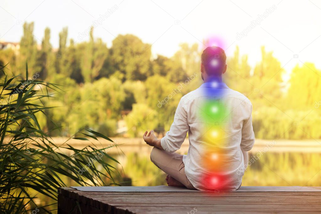 Man meditating on wooden pier near river, back view. Scheme of seven chakras, illustration