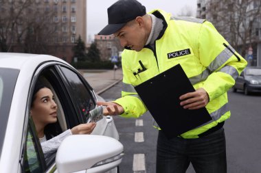 Kadın, arabanın camından polise rüşvet veriyor.