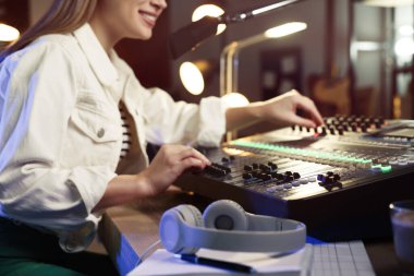 Modern stüdyoda radyo sunucusu olarak çalışan bir kadın.