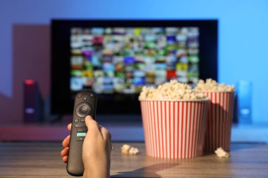 Televizyonda uzaktan kumandayla kanal değiştiren kadın, yakın çekim.