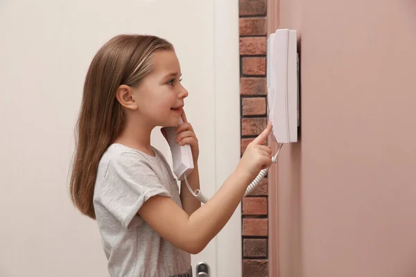 Cute Little Girl Answering Intercom Call Indoors — стоковое фото